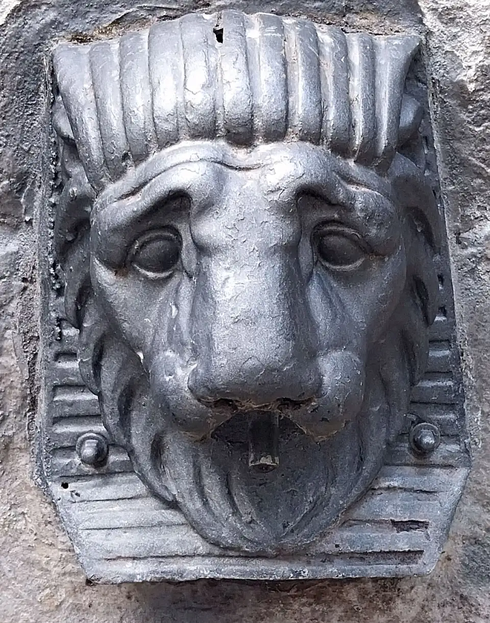 Testa di leone in metallo che fa da bocca alla Fuente del Perro