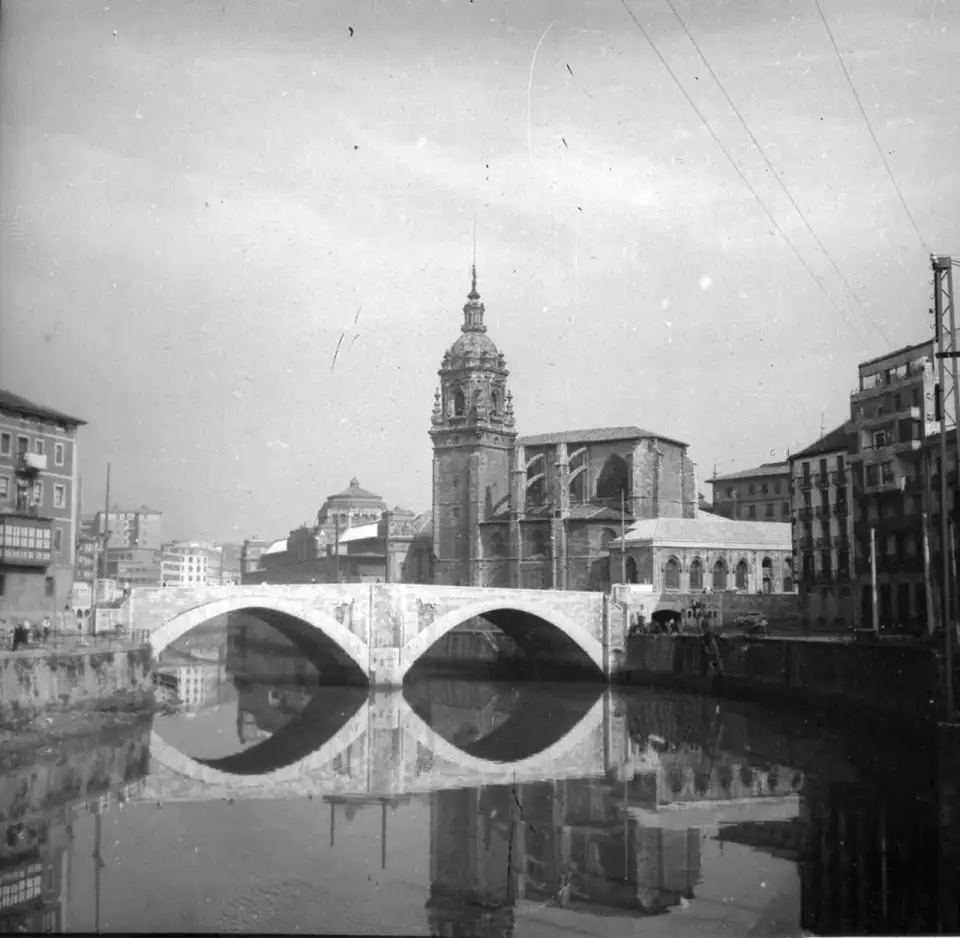 Fotografia antiga em preto e branco da igreja e da ponte de San Antón refletidas na ria
