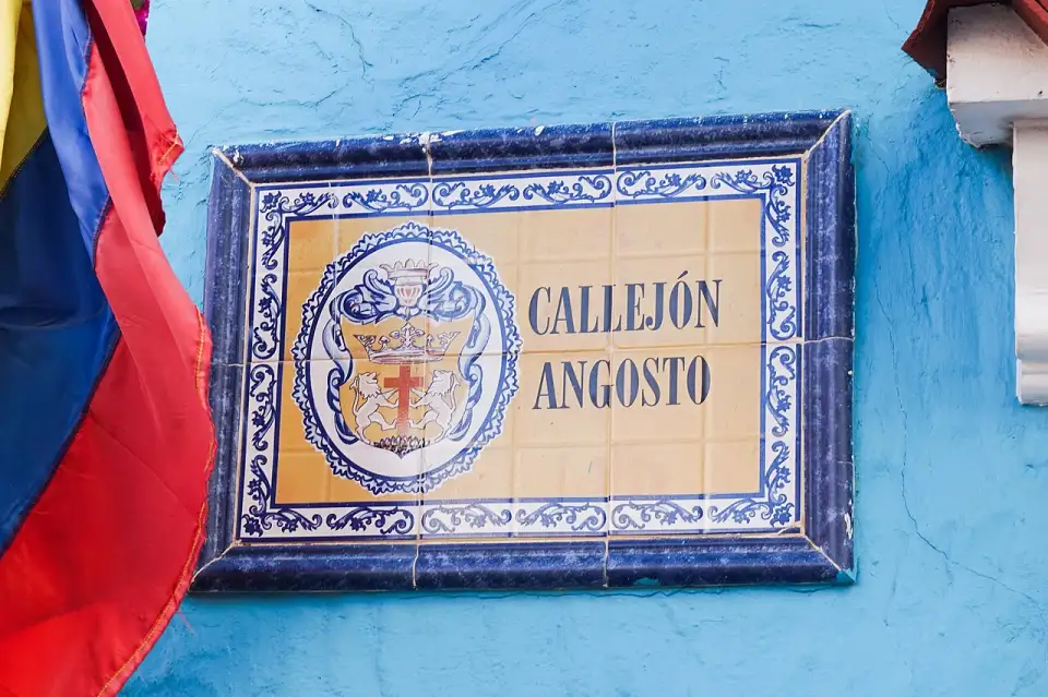 Plaque en azulejos portant le nom Callejón Angosto sur un mur bleu