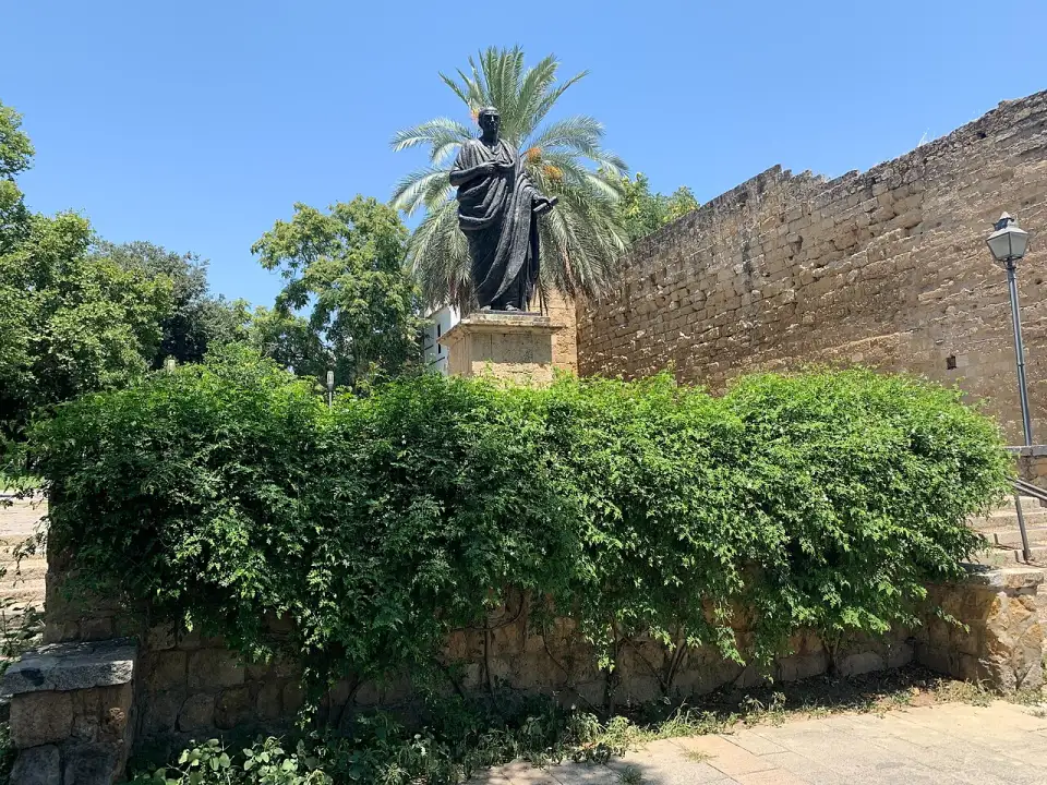 Statua in bronzo di Seneca in toga su un piedistallo accanto alle mura, in calle Cairuán