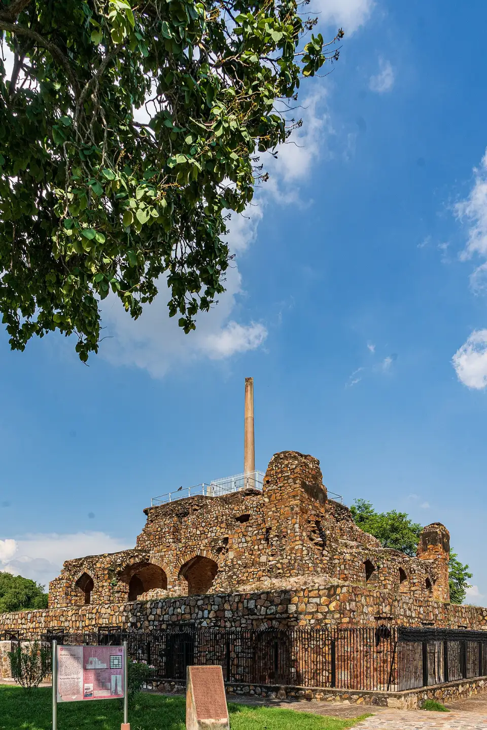 Pirámide de arcos en ruinas con la columna de Ashoka en Feroz Shah Kotla