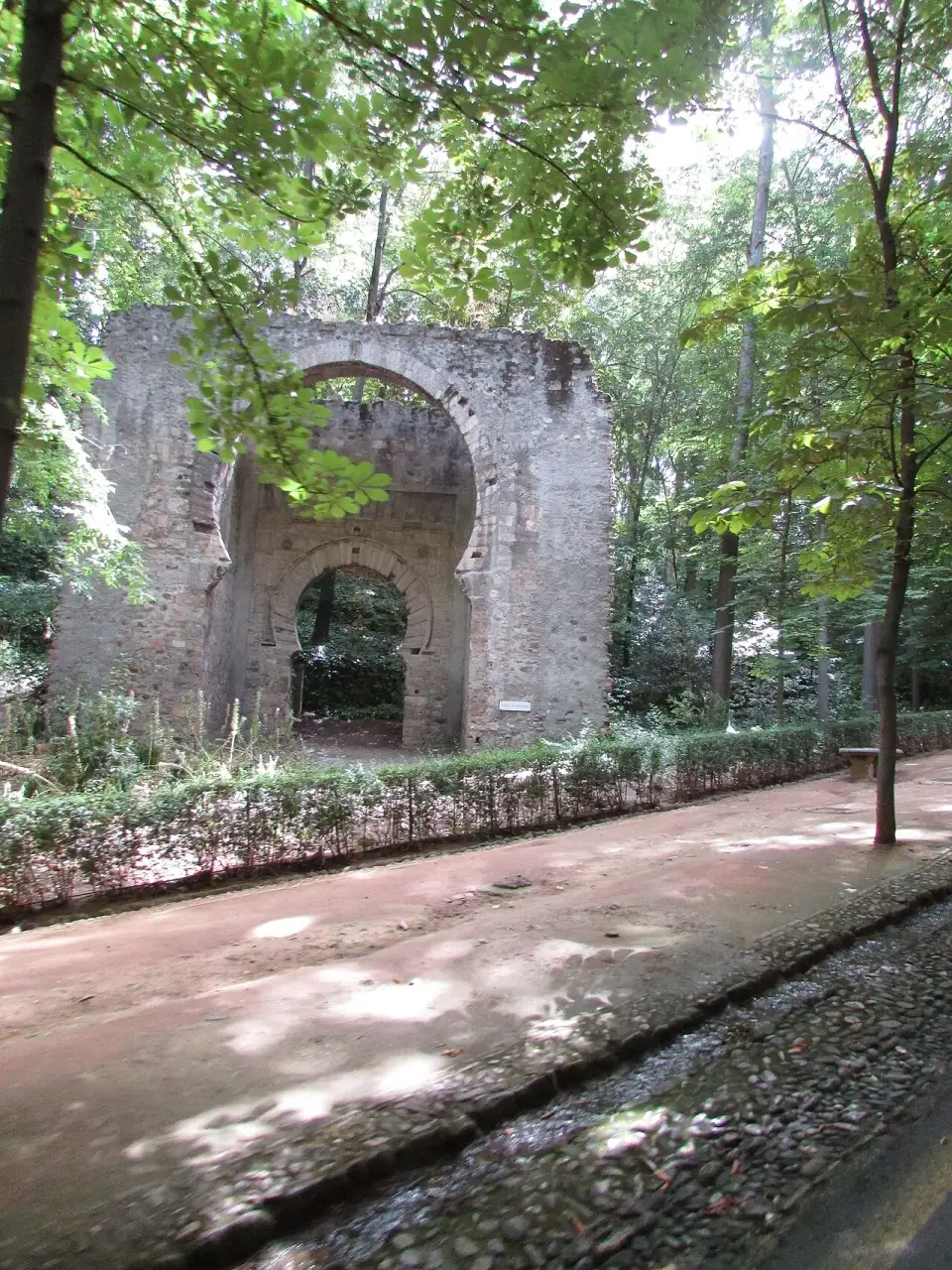 Resti ricostruiti della Puerta de Bib-Rambla, con due archi a ferro di cavallo, tra gli alberi del bosco dell’Alhambra