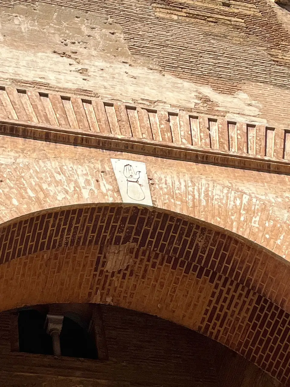 Mano scolpita su una lastra di marmo nella chiave dell’arco della Puerta de la Justicia