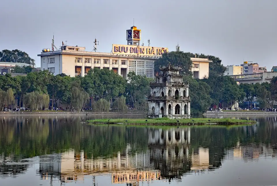 Der Schildkrötenturm im Hoàn-Kiếm-See in Hanoi, dahinter die Hauptpost