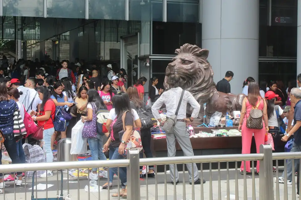 Um dos leões de bronze do HSBC diante da entrada da torre, cercado de gente num domingo