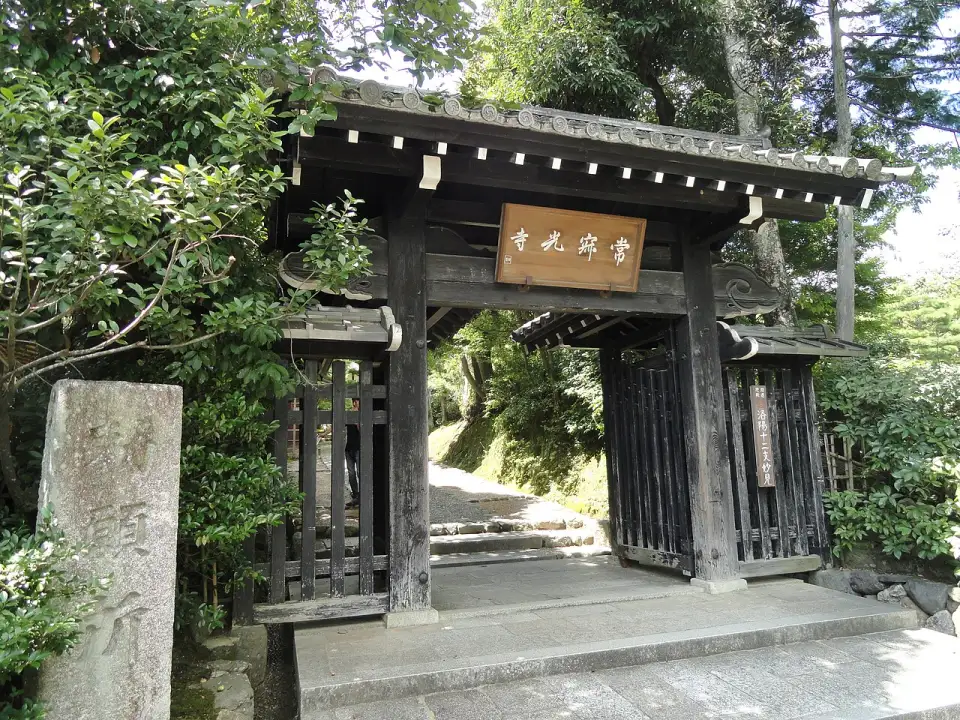 The wooden gate of Jōjakkō-ji among trees, with the temple’s name board