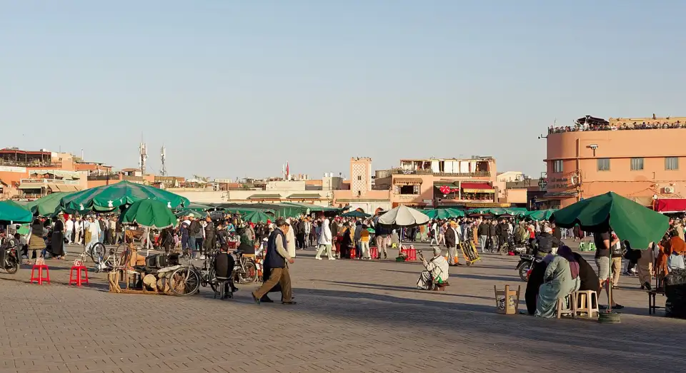 Vista ampla da praça Jemaa el-Fna com barracas e toldos verdes