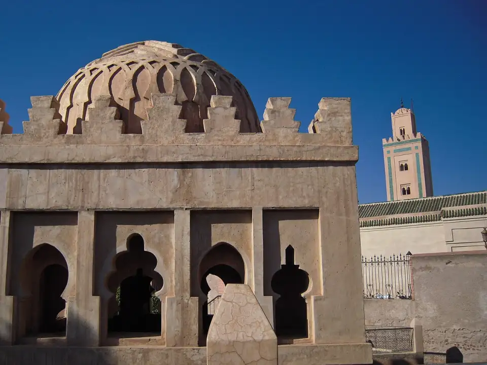 Cúpula almorávida com arcos lobulados e ameias, com um minarete atrás