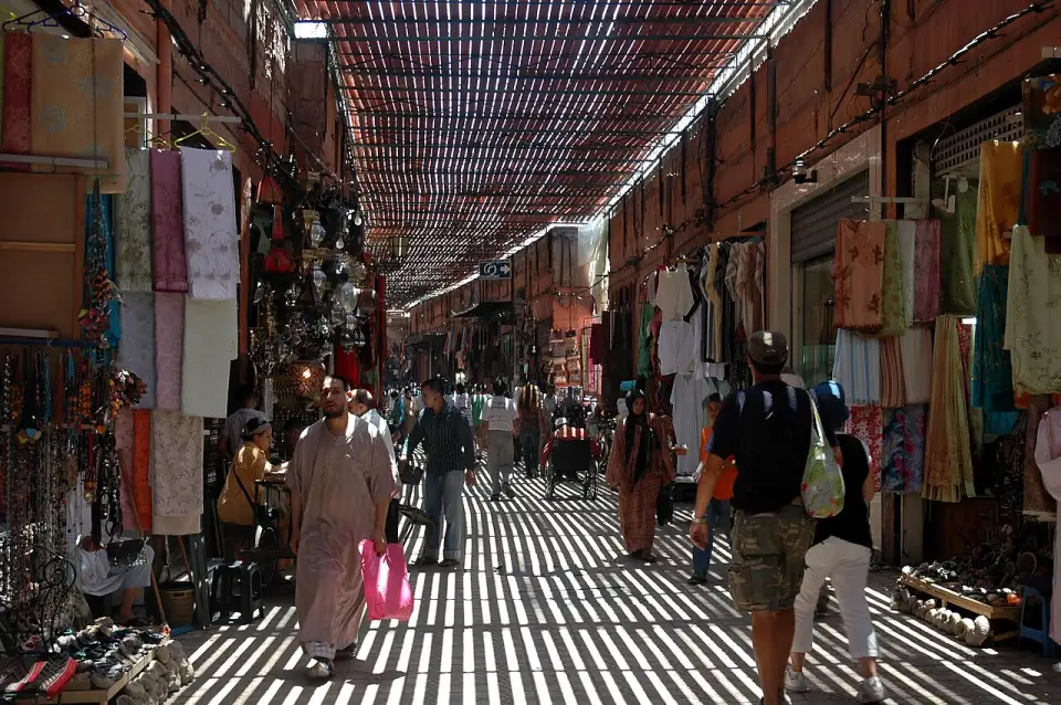 Rue couverte du souk Semmarine avec boutiques de tissus et lumière filtrée par des lattes