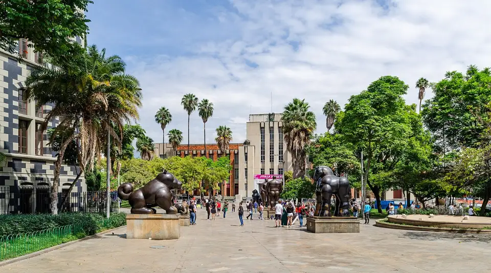 Place Botero avec des sculptures en bronze, des palmiers et le musée d'Antioquia au fond