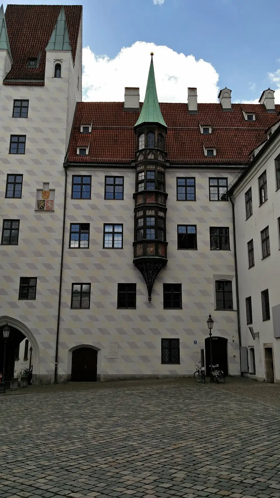 Innenhof des Alten Hofs mit weißen, rautenverzierten Fassaden und dem gotischen Erker an der Ecke