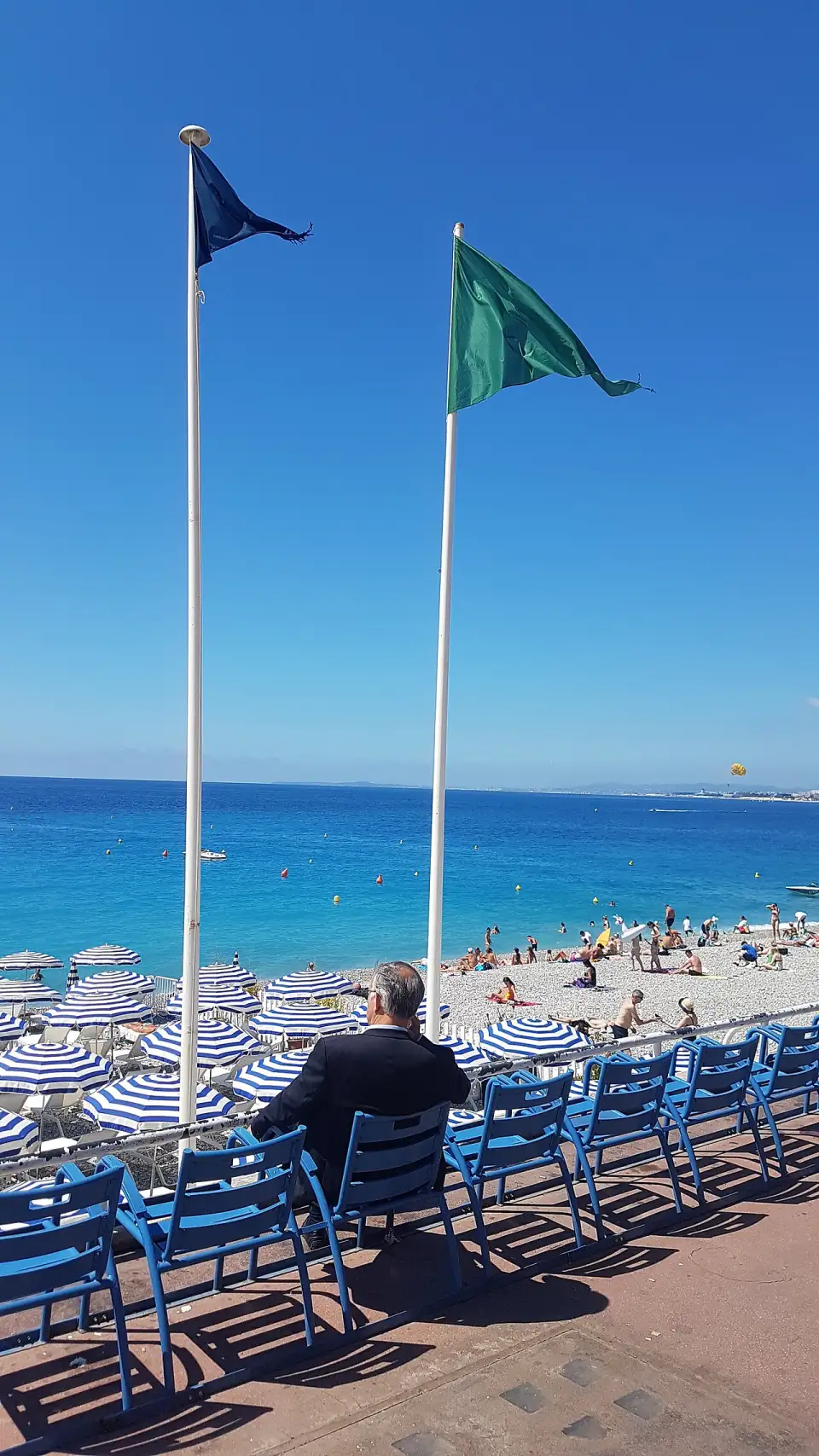Chaises bleues en métal sur la promenade des Anglais, tournées vers la plage