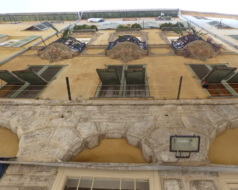 Sacadas de ferro forjado sobre mísulas de pedra na fachada do palácio Lascaris