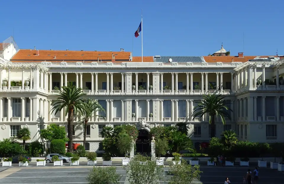 Il palazzo della Prefettura di Nizza, color crema, con la loggia a colonne e le palme davanti