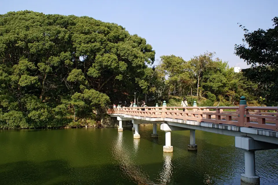 A colina arborizada de Chausuyama e a ponte vermelha sobre o lago Kawazoko
