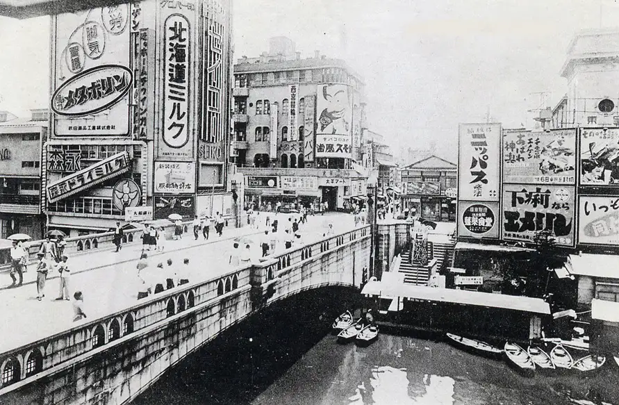 Fotografia antiga em preto e branco da ponte Ebisu e seus anúncios