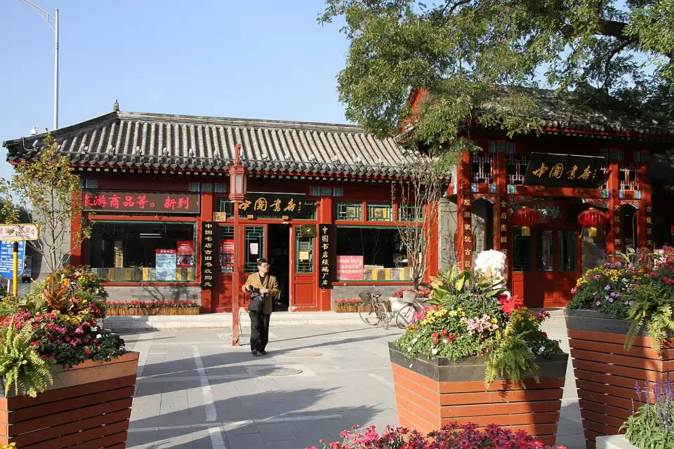 Eine traditionelle Buchhandlung in der Liulichang mit grauem Dach, roten Säulen und schwarz-goldenen Schildern