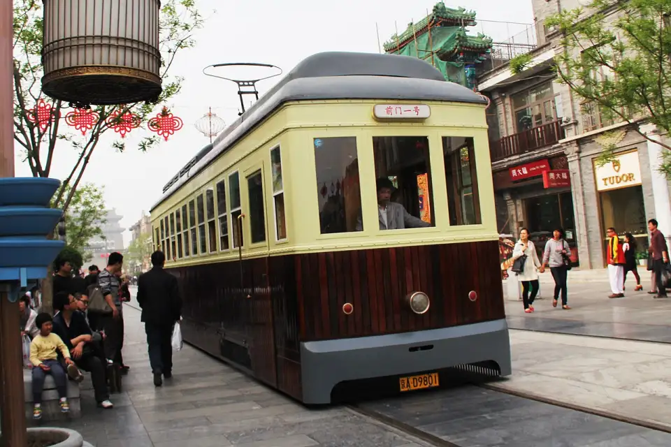 Eine Straßenbahn im Retrostil in der Fußgängerzone Qianmen mit Laternen und Läden