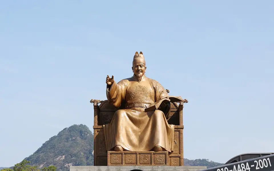 Golden statue of King Sejong seated on his throne, with Mount Bugaksan in the background