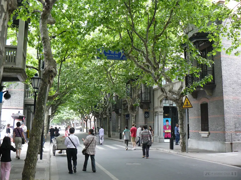 Tree-lined street in Xintiandi with brick houses and passers-by